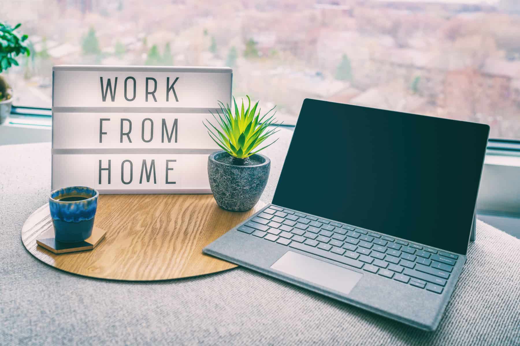 Laptop mit Leuchttafel daneben mit der Aufschrift "Work from Home"